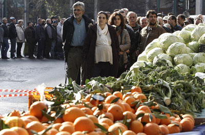 People line up for fruits and vegetables freely distributed by farmers during a protest against high production costs outside the Agriculture Ministry in Athens